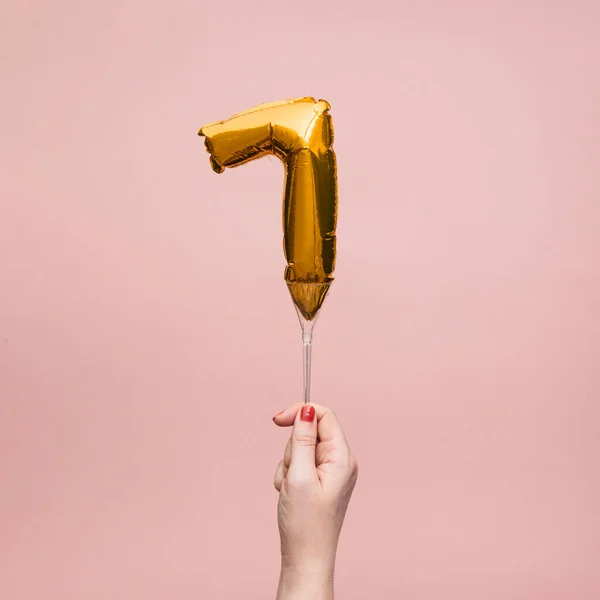 Kvinnlig hand som håller en nummer 7 födelsedag firande guld ballong — Stockfoto