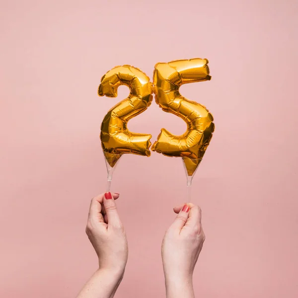 Mão feminina segurando um número 25 aniversário celebração balão de ouro — Fotografia de Stock