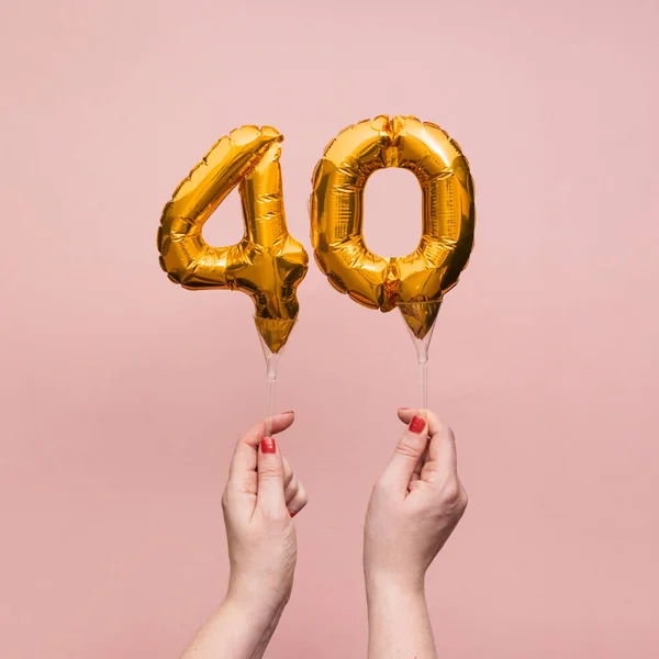 Mano femminile che tiene un numero 40 anniversario di compleanno palloncino d'oro celebrazione — Foto Stock