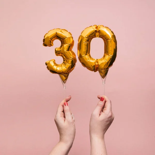 Mano femenina sosteniendo un globo de oro de celebración de aniversario número 30 —  Fotos de Stock