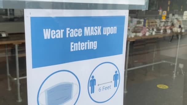 Beskyttende ansigtsmaske kræves tegn i et butiksvindue – Stock-video