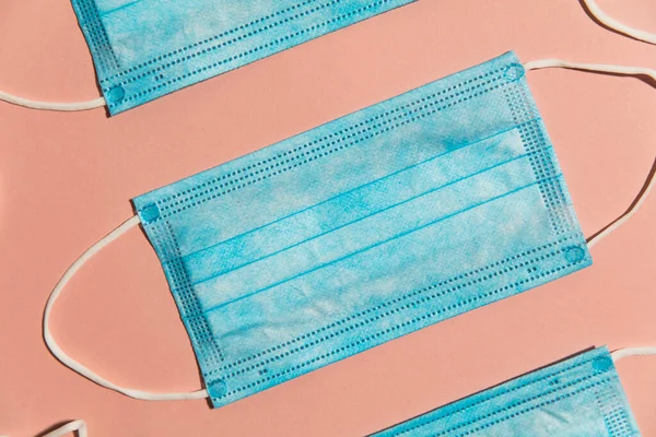 Blauw chirurgisch medisch masker plat compositie op een roze achtergrond — Stockfoto