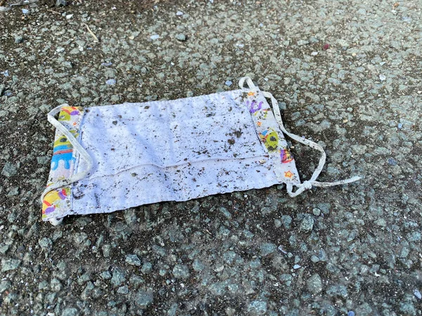 Coronavirus Disposable protective face mask discarded on the street