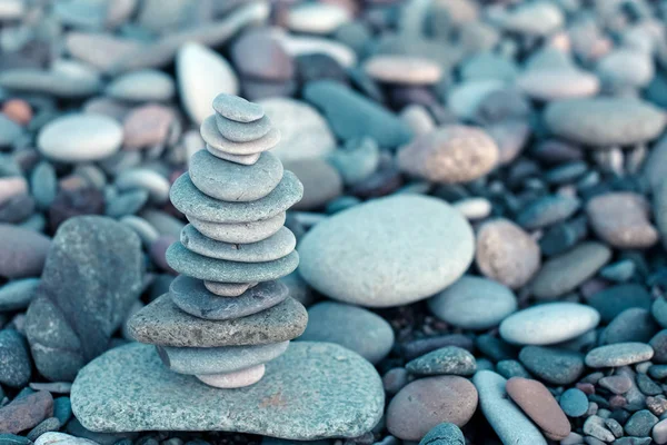 Stack of stones on beach - nature background. Stone cairn on stones background, pebbles and stones. Concept balance