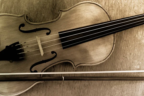 Closeup of a violin and bow horizontal image on wooden background toned sepia. Retro style.
