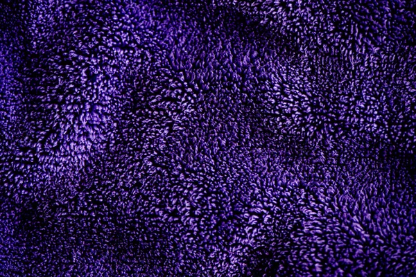 Blue dark delicate soft background of fur plush smooth fabric. Texture of purple soft fleecy blanket textile
