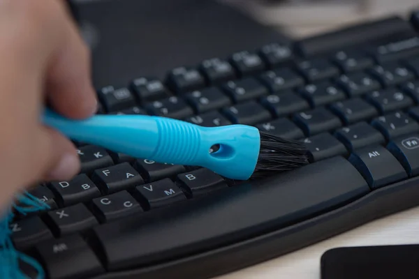 Cleaning and caring computer keyboard with a blue brush from dus