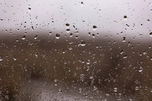 Water drops after the rain in a dark window glass