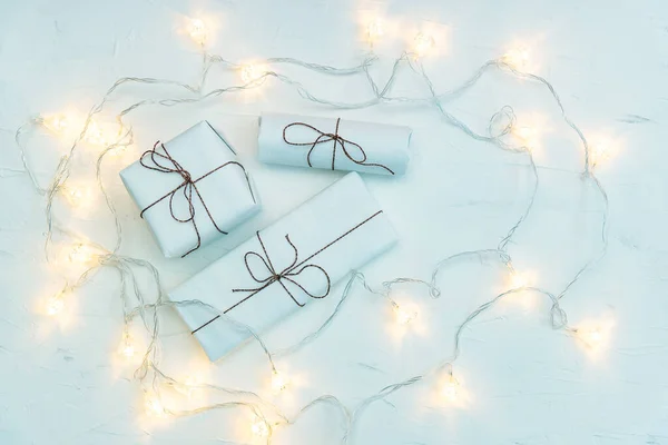 Flat lay of mockup presents for Christmas. Decorative glowing garlands and blank packages, gifts in boxes, tied with ribbon. Winter holidays and New Year celebration, festivity mood, wrapped packages