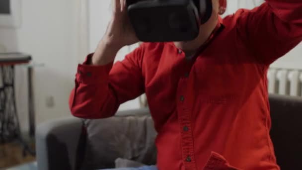 穿红色衬衫的男人穿上衣服 在家里的虚拟现实谷歌 — 图库视频影像