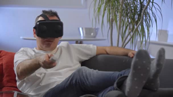 ソファ仮想現実グーグルに を楽しんでの白いシャツの男性 — ストック動画