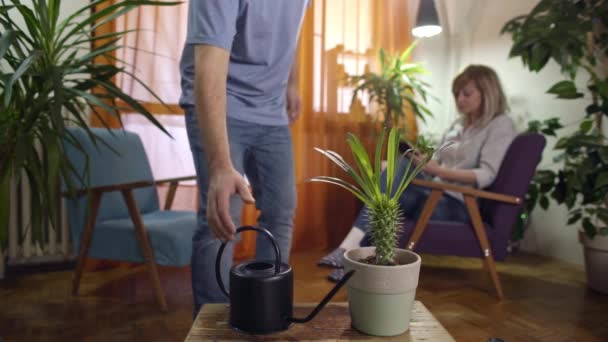 Hombre Riego Pulverización Planta Hogar Moderno Mujer Lectura Tableta — Vídeos de Stock