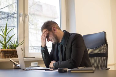 office baş ağrısı içinde laptop dizüstü bilgisayar kağıtları telefon migren ile pencere siyah masasının üzerinde işadamı