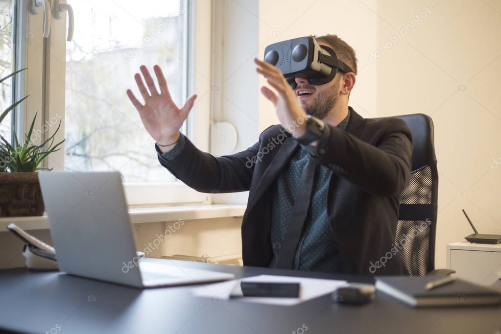 businessman finishes his work and taking virtual reality goggles on by window black table with notebook papers phone VR