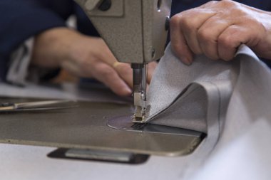 Kanepe için malzeme dikiş yaşlı bir kadınla bir mobilya fabrikasında closeup