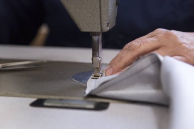 Kanepe için malzeme dikiş yaşlı bir kadınla bir mobilya fabrikasında closeup