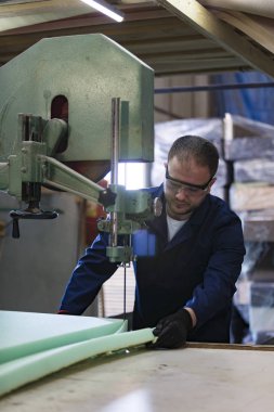 Genç adam bir mobilya fabrikasında kanepe için köpük kesme