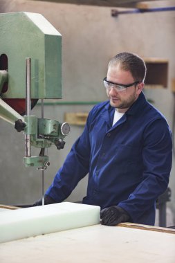 Kanepe için köpük kesme bir mobilya fabrikasında genç bir adam portresi