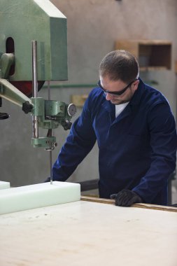 Kanepe için köpük kesme bir mobilya fabrikasında genç bir adam portresi