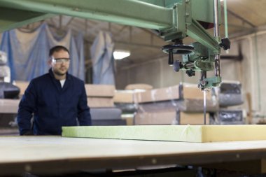Genç adam bir mobilya fabrikasında kanepe için köpük kesme
