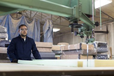 Genç adam bir mobilya fabrikasında kanepe için köpük kesme