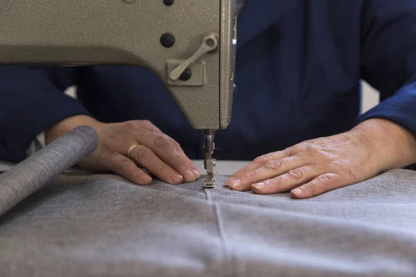 Крупный план пожилой женщины на мебельной фабрике, которая шьет материал для дивана — стоковое фото