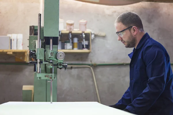 Портрет молодого человека на мебельной фабрике, разрезающего пену для дивана — стоковое фото