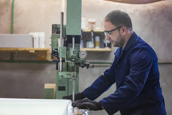 Portrait of a young man in a furniture factory cutting the foam for the sofa