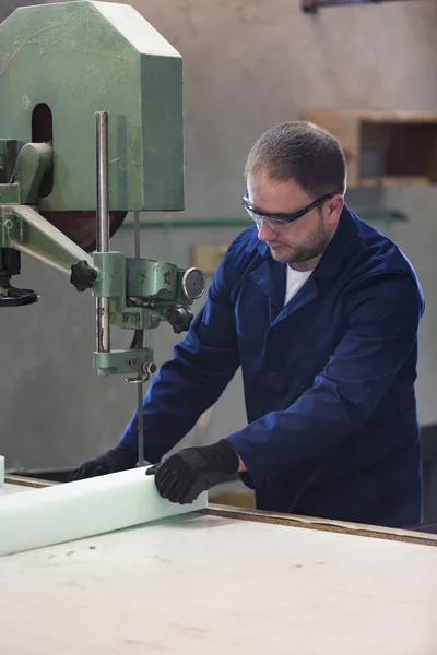 Portrait of a young man in a furniture factory cutting the foam for the sofa — Stock Photo, Image