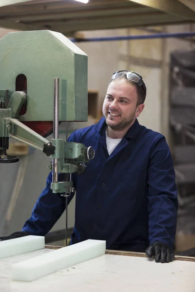 Portret van een jonge man in een meubelfabriek snijden het schuim voor de Bank — Stockfoto