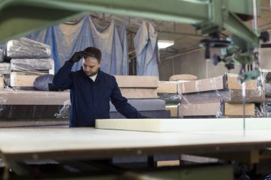 Genç adam bir mobilya fabrikasında kanepe için köpük kesme