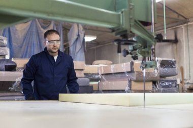 Genç adam bir mobilya fabrikasında kanepe için köpük kesme