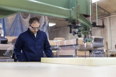 Genç adam bir mobilya fabrikasında kanepe için köpük kesme