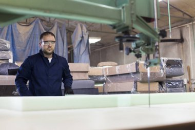 Genç adam bir mobilya fabrikasında kanepe için köpük kesme