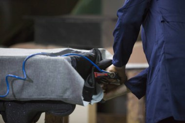 Bir mobilya fabrikasında kanepe ve bir kısım bir zımba ile birlikte koyar bir delikanlı closeup