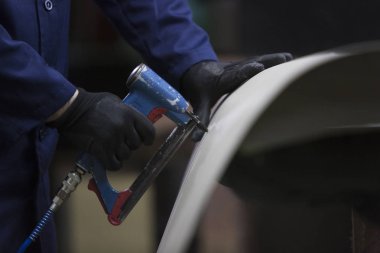 Bir mobilya fabrikasında kanepe ve bir kısım bir zımba ile birlikte koyar bir delikanlı closeup