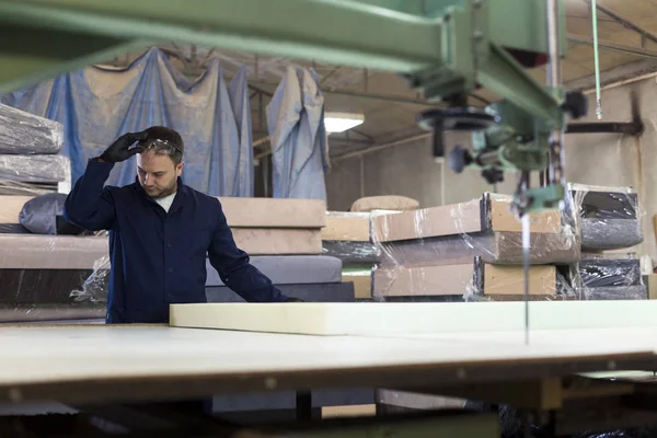 Young man in a furniture factory is measuring the foam for the sofa.