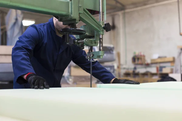 Jonge man in een meubelfabriek is snijden het schuim voor de Bank — Stockfoto