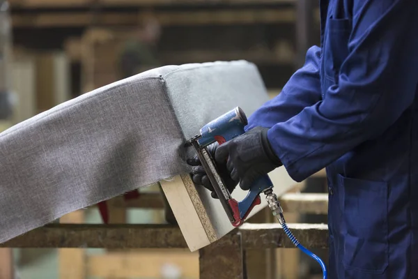 Close-up van een jonge man in een meubelfabriek die samen een deel van de Bank met een nietmachine stelt — Stockfoto