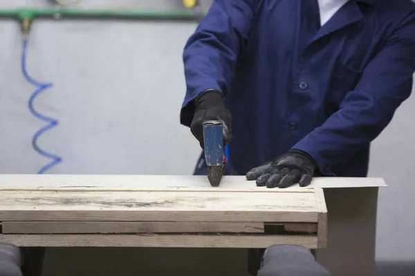 Primer plano de un joven en una fábrica de muebles que junta una parte del sofá con una grapadora — Foto de Stock