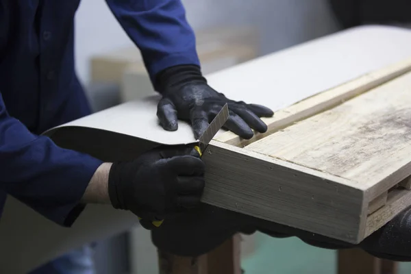Primo piano di un giovane in una fabbrica di mobili che taglia le parti in eccesso del divano — Foto Stock