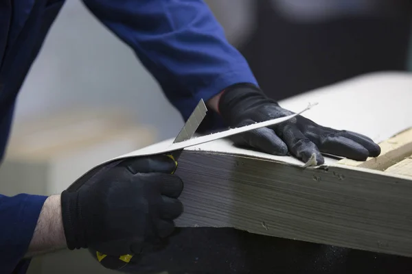 Closeup of a young man in a furniture factory who cut the excess parts of the sofa