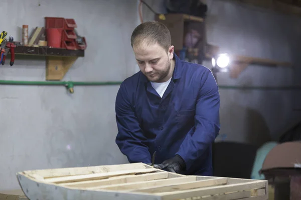 Close-up van een jonge man in een meubelfabriek die snijd de overtollige delen van de Bank — Stockfoto
