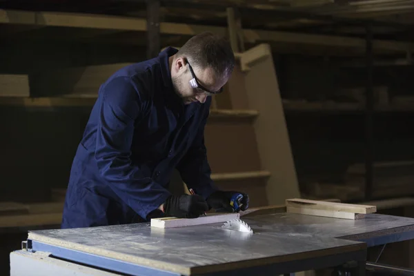 Joven en una fábrica de muebles cortando las piezas de madera para el sofá — Foto de Stock