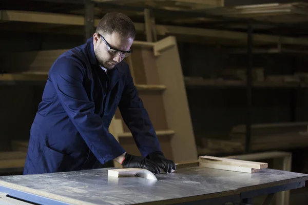 Joven en una fábrica de muebles cortando las piezas de madera para el sofá — Foto de Stock