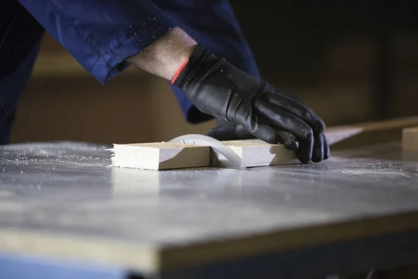 Close up of a young man in a furniture factory cutting the wooden pieces for the sofa