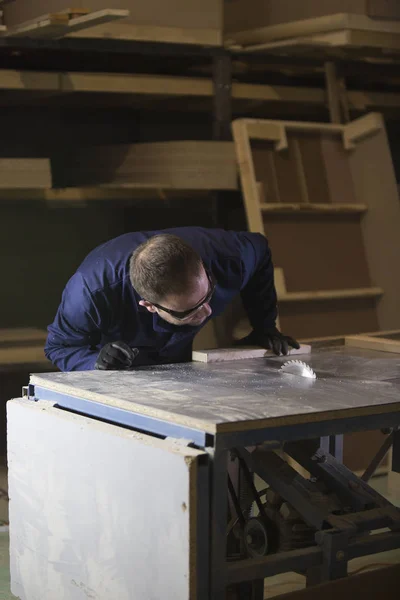 Молодой человек на мебельной фабрике режет деревянные детали для дивана — стоковое фото