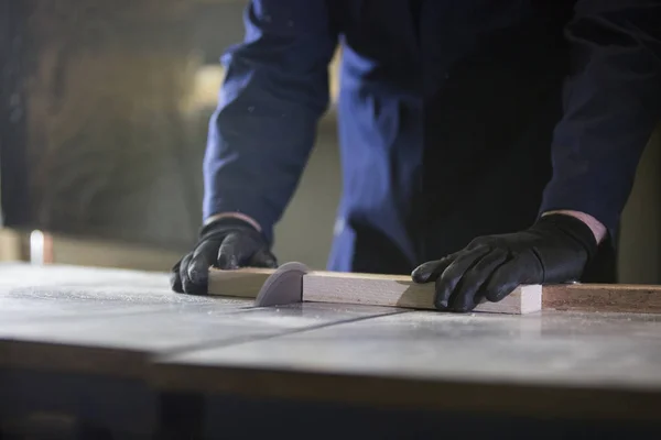 Close up of a young man in a furniture factory cutting the wooden pieces for the sofa