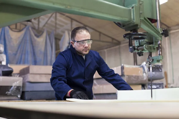 Молодой человек на мебельной фабрике режет пену для дивана Лицензионные Стоковые Фото