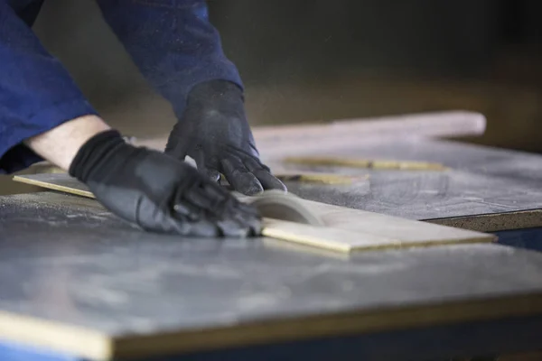 Close up of a young man in a furniture factory cutting the wooden pieces for the sofa